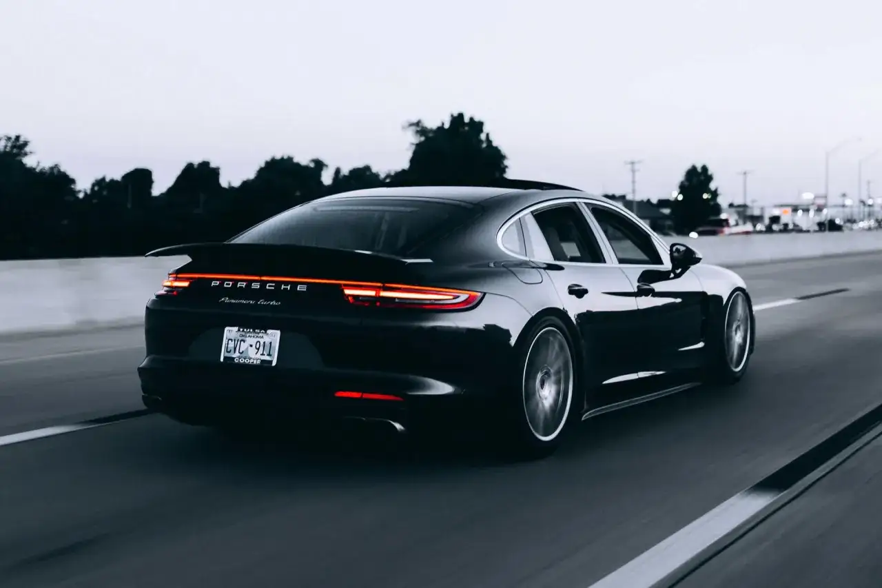 Czarny Porsche Panamera Turbo jedzie autostradą. Tablica rejestracyjna CVC-911. Limit 150 tys. VAT-26.