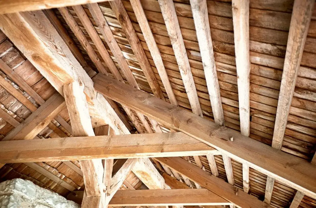 Structure en bois d'un toit ancien. Les poutres massives et les chevrons témoignent d'un savoir-faire traditionnel, essentiel pour estimer le prix charpente.