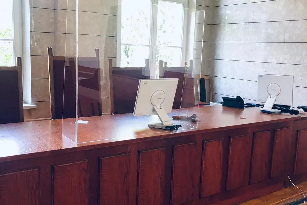 Przezroczyste przegrody na biurku w sali sądowej, przygotowane na rozprawę rozwodową.