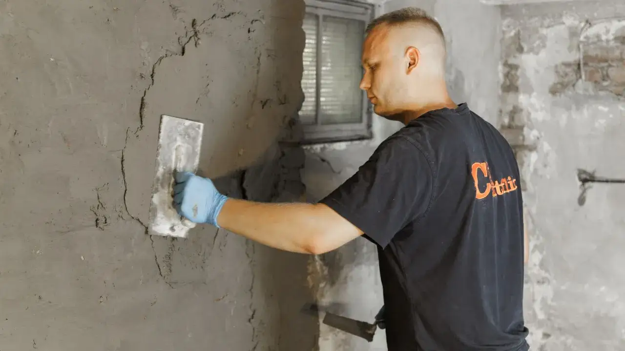 Mann verputzt Wand im Keller eines Altbaus. Professionelle Arbeiten zum keller trockenlegen altbau.