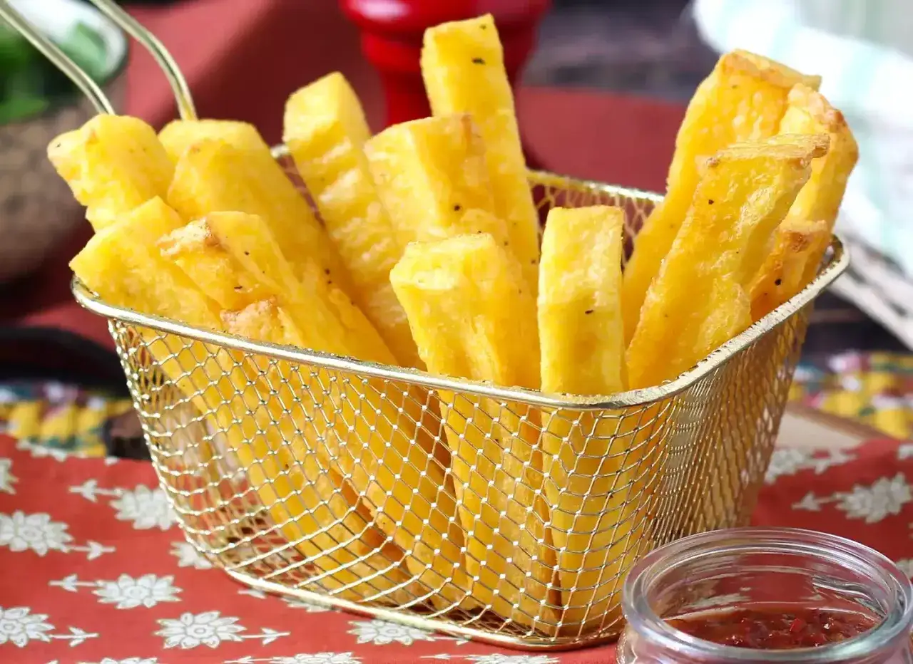 Crujientes bastones de polenta a la plancha en una cesta dorada, listos para ser disfrutados con una salsa picante.