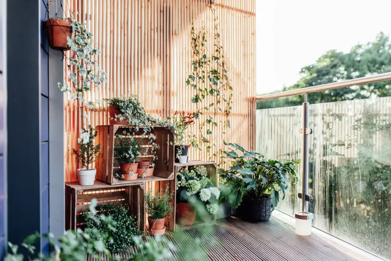 Ideas balcones muy peque&ntilde;os: plantas en macetas y cajas de madera crean un oasis verde.