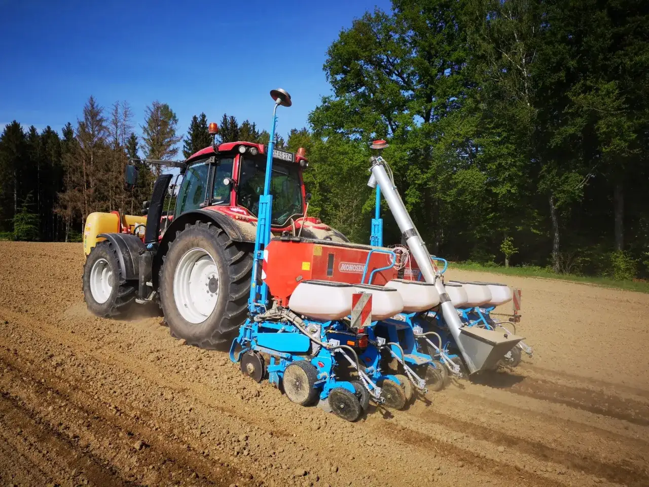 Traktor mit S&auml;maschine auf einem Feld. Der richtige mais spritzen zeitpunkt ist entscheidend f&uuml;r eine gute Ernte.