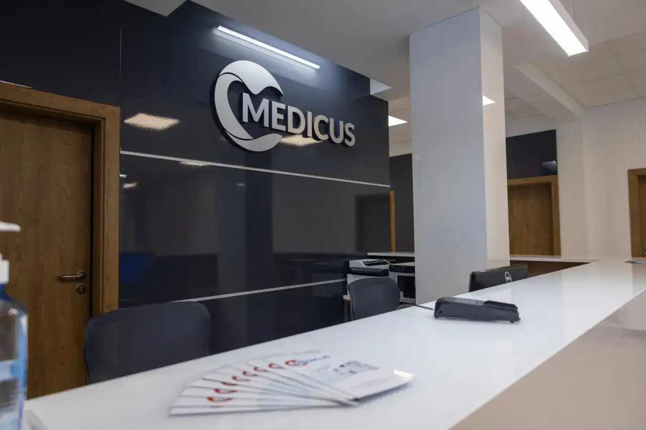 Recepcja centrum medycznego Medicus z logo, białym blatem i drzwiami.