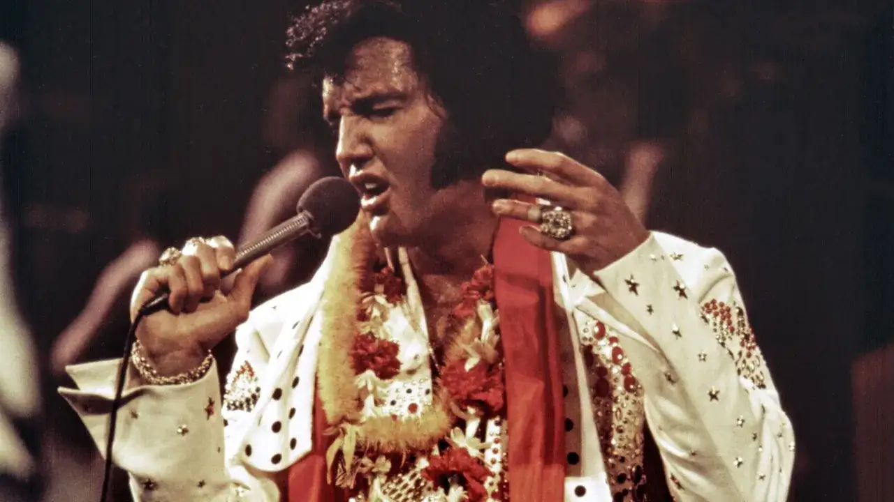 Elvis Presley singt in Hawaii, tr&auml;gt eine Blumenkette und einen glitzernden Anzug.