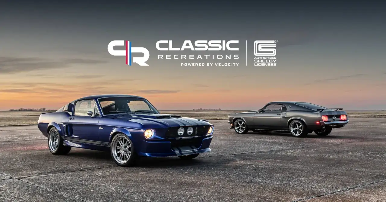 Dwa klasyczne samochody, niebieski i szary mustang shelby, stoją na tle zachodzącego słońca.