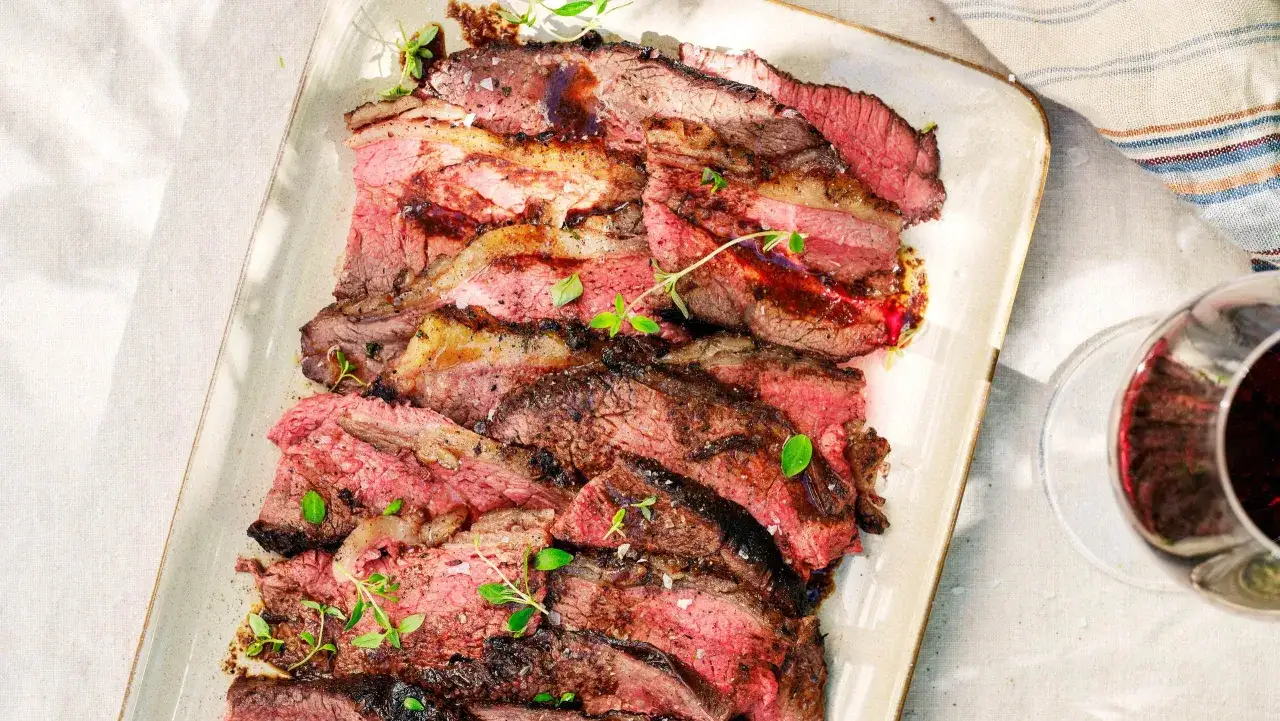 Skivad picanha styckdetalj, perfekt grillad med saftig rosa kärna och en härlig yta. Garnerad med färska örter.