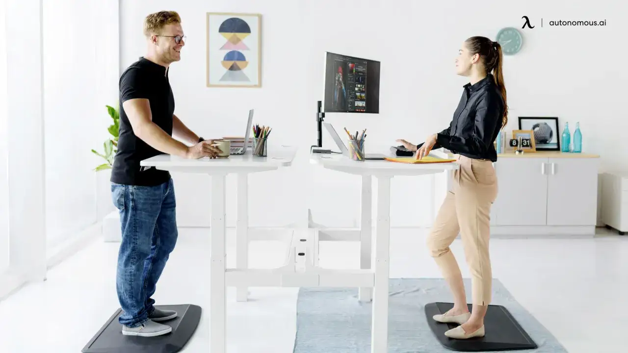 Un homme et une femme travaillent sur des bureaux r&eacute;glables en hauteur, profitant des bienfaits de rester debout toute la journ&eacute;e.