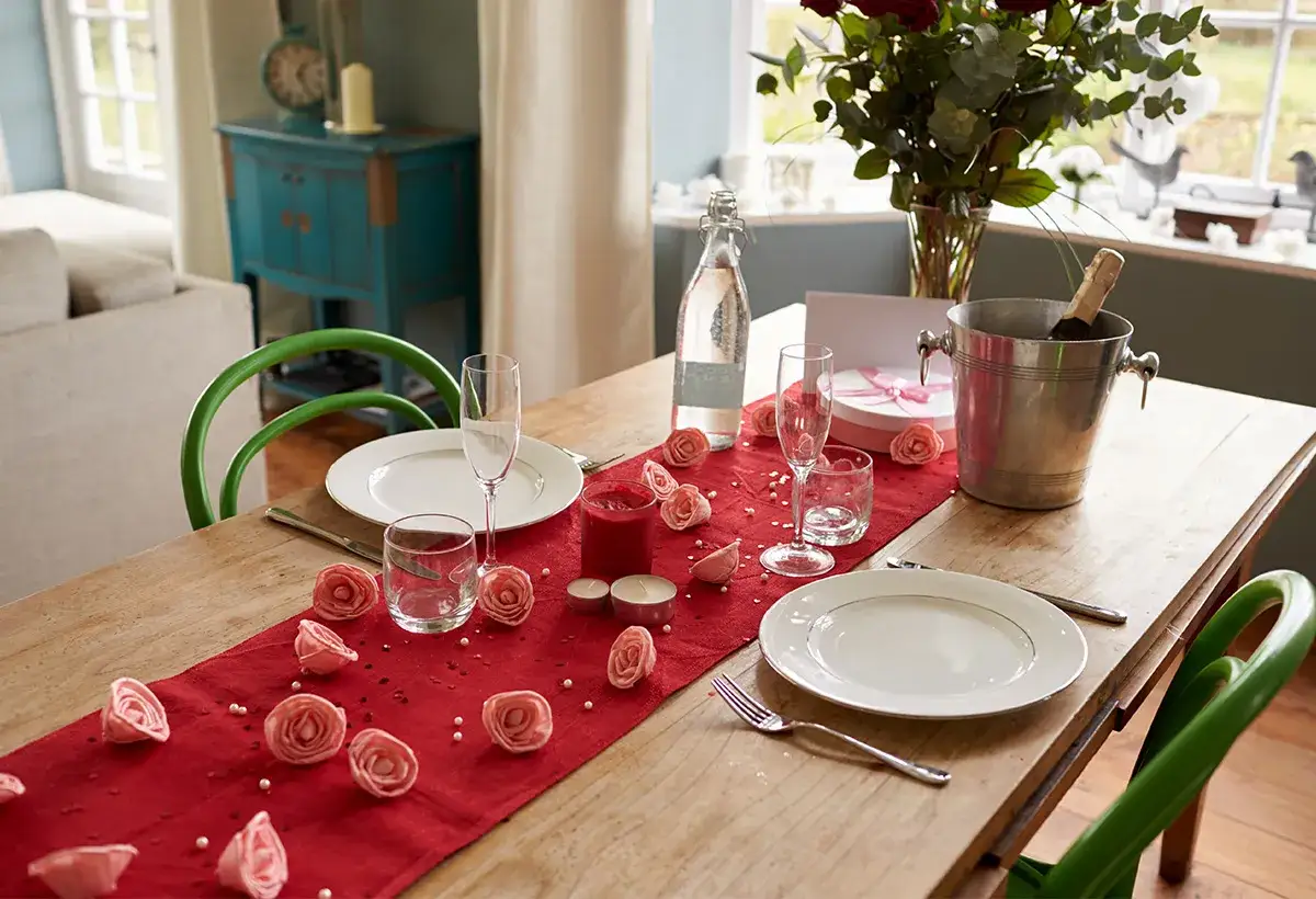 Table dress&eacute;e pour une **journ&eacute;e Saint-Valentin** romantique avec des roses, des bougies et du champagne.