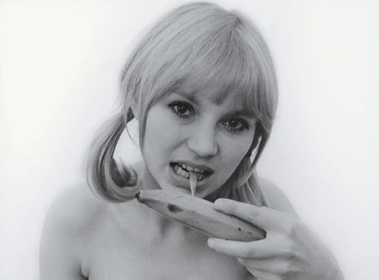 Natalia LL i sztuka konsumpcyjna: młoda kobieta z warkoczami je banana, z którego kapie płyn.