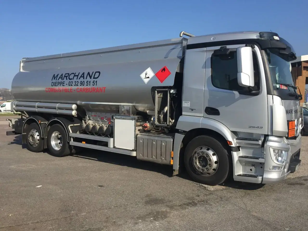 Camion-citerne argenté de la société MARCHAND, transportant du **gasoil poids lourd**. Il arbore des pictogrammes de danger.