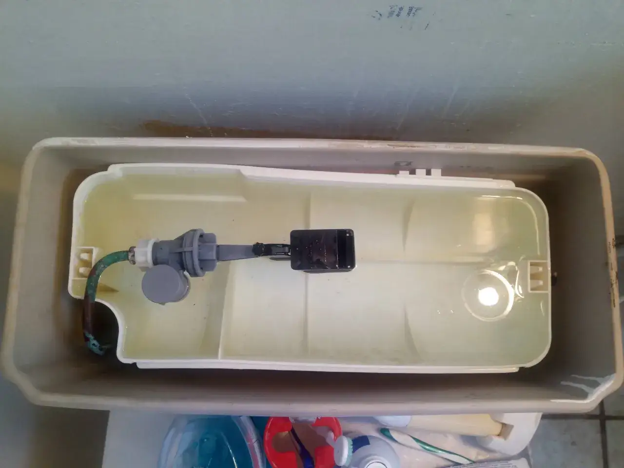Inside a toilet tank, a fill valve and float assembly are visible. This image can help you learn how to fix a running toilet.