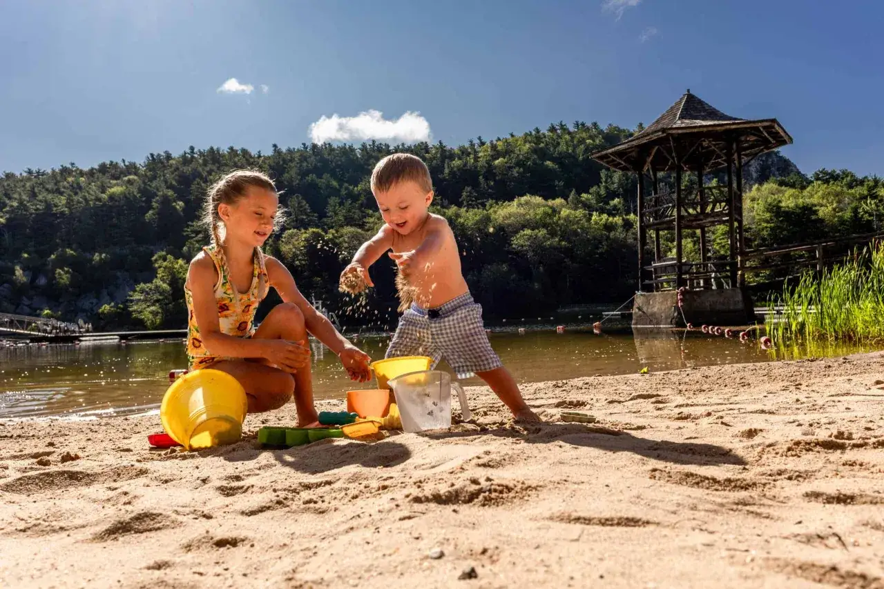 Dzieci budują zamek z piasku nad jeziorem. Idealne miejsce, gdzie na wakacje z dziećmi.