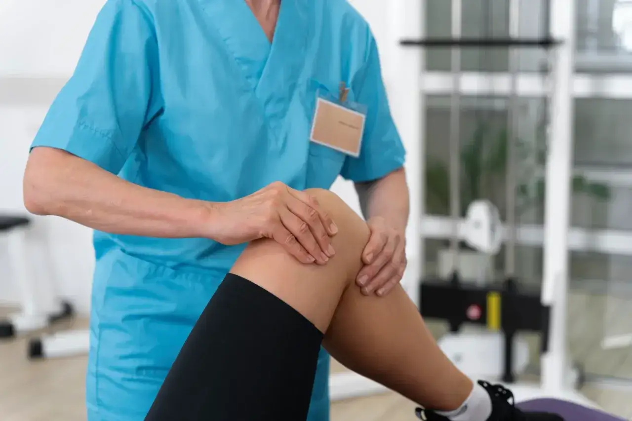 Fizjoterapeuta bada kolano pacjenta, oceniając jaka rehabilitacja na kolano będzie najlepsza.