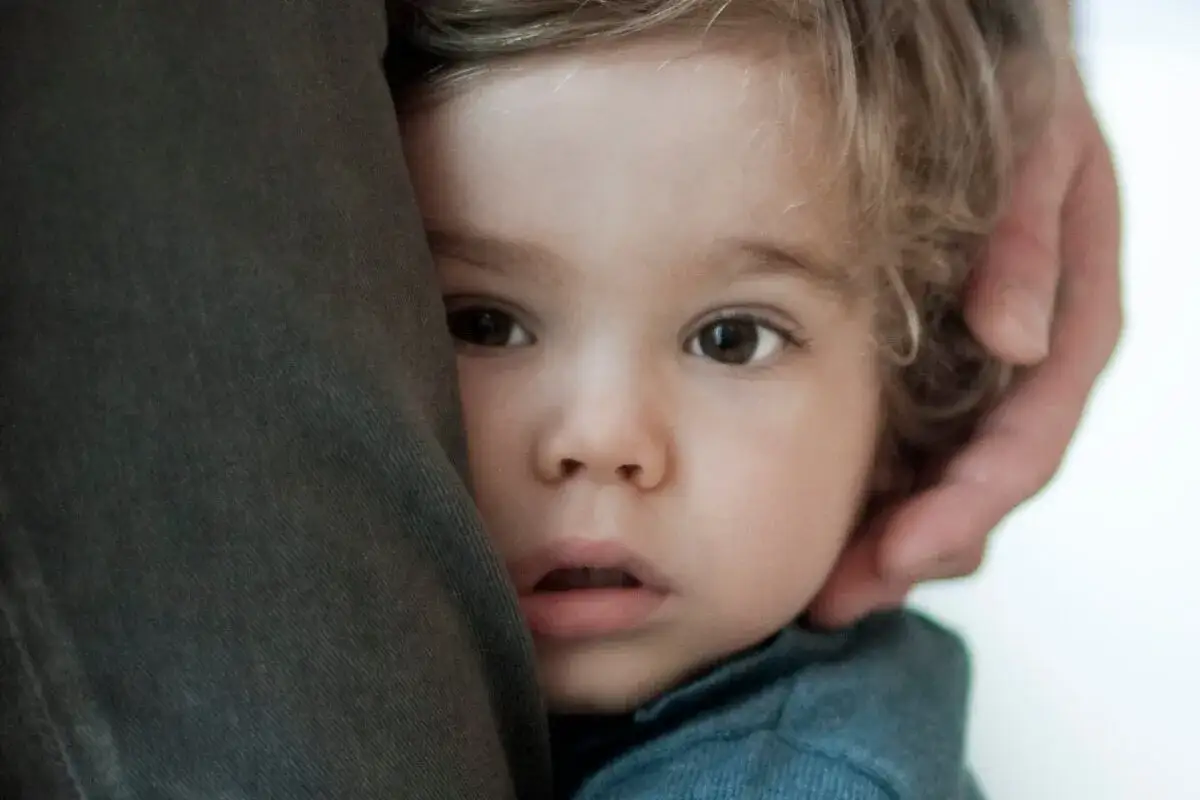 Un ni&ntilde;o con ojos curiosos se esconde detr&aacute;s de una tela, mostrando la timidez de los ni&ntilde;os introvertidos.