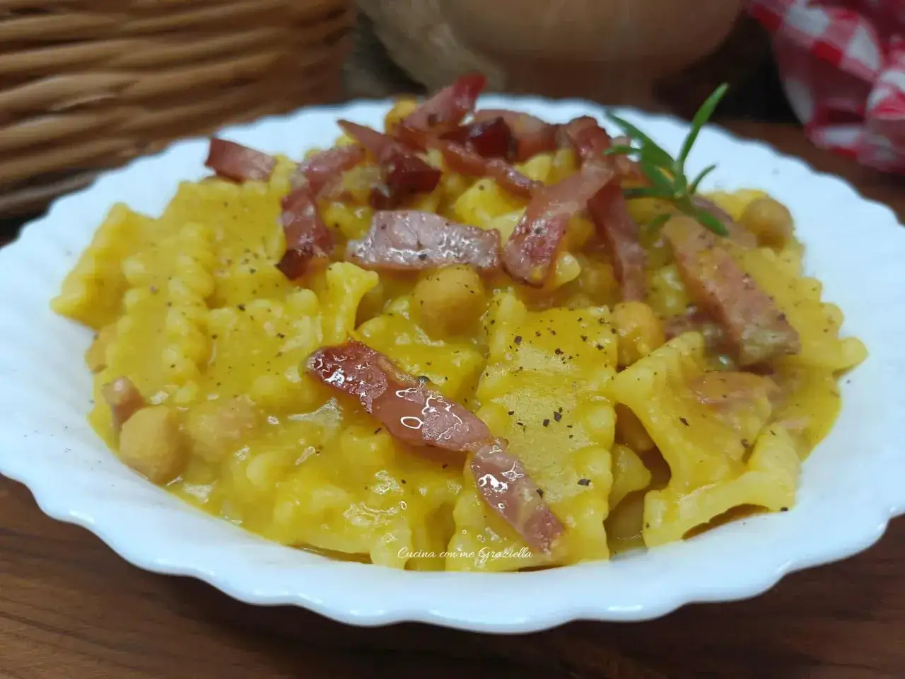 Piatto di pasta con speck croccante e ceci, avvolta in una cremosa salsa allo zafferano. Un'esplosione di sapori.