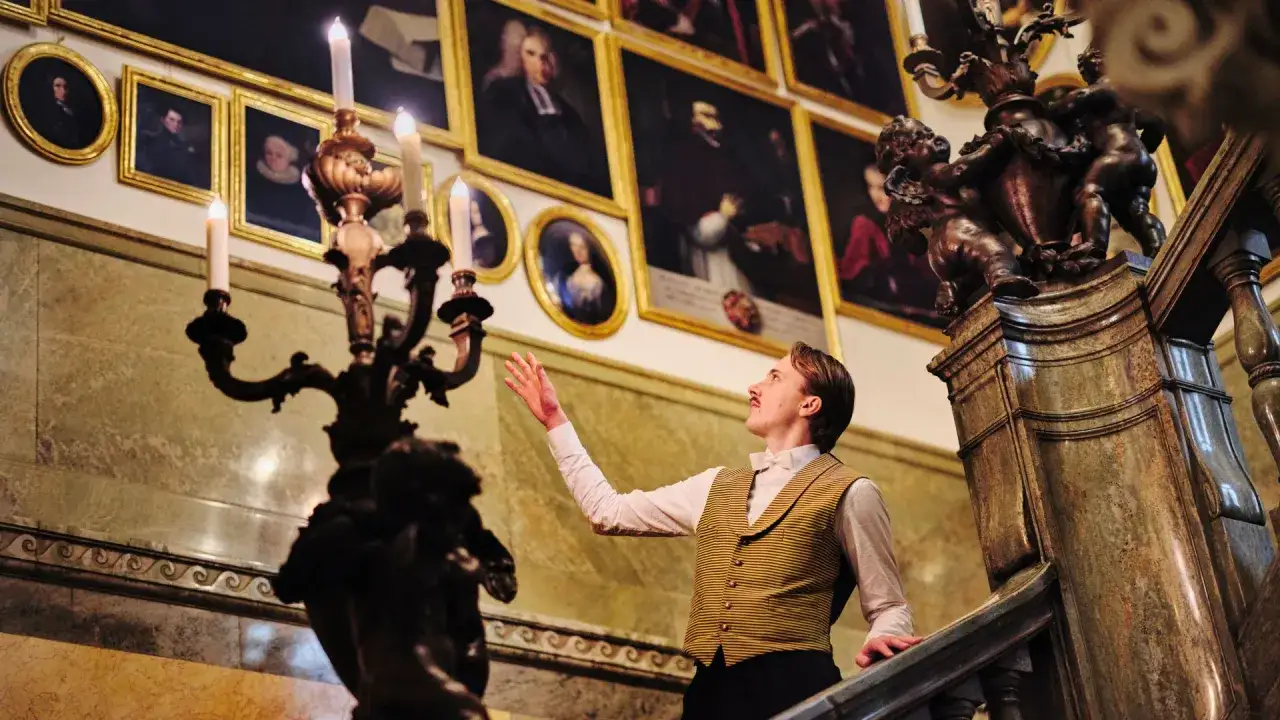Man i historisk klädsel beundrar konst på en trappa i ett av Stockholms museer.