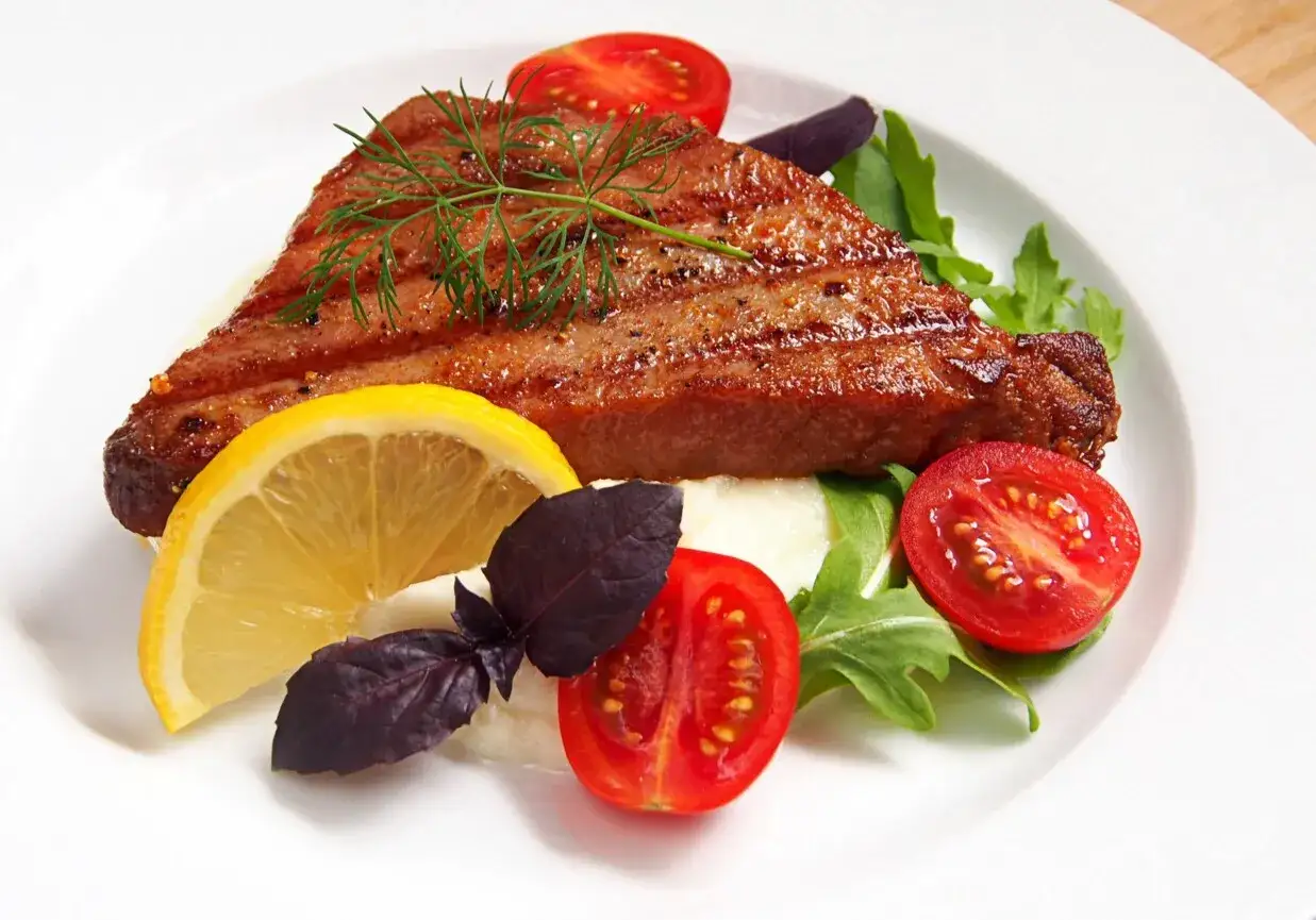 Grillowany stek z tuńczyka z cytryną, pomidorkami i rukolą. Pyszne danie, które zachwyci każdego smakosza.