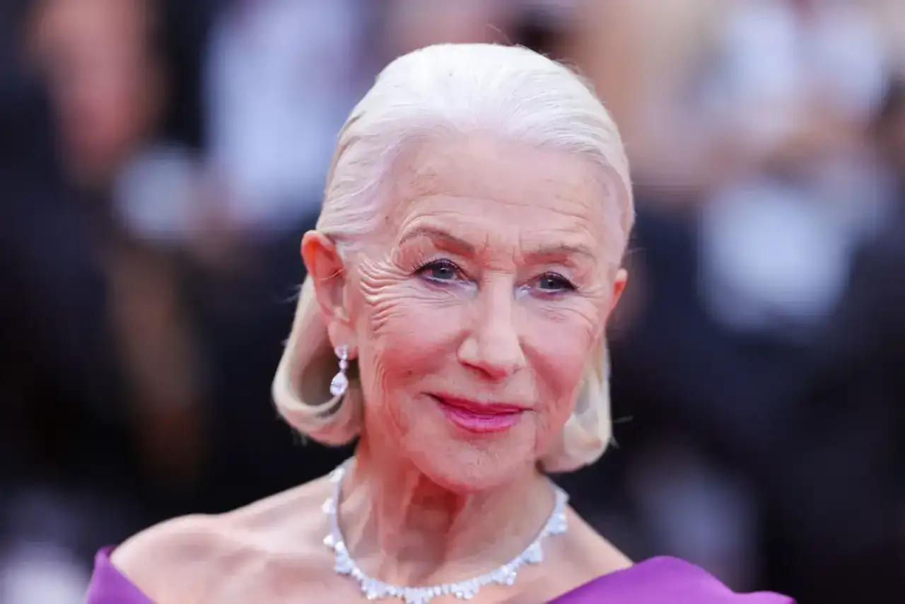 Helen Mirren, con su cabello plateado y las canas que adornan su frente, sonríe con elegancia.