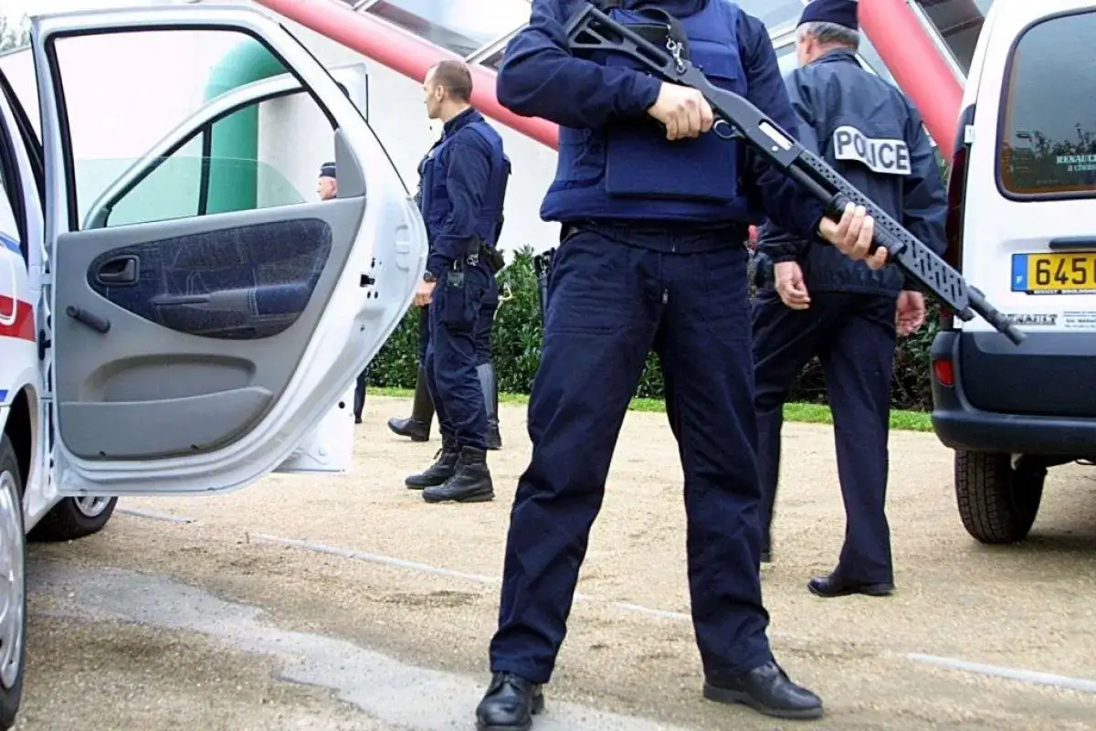 Un policier national tient un fusil &agrave; pompe, pr&ecirc;t &agrave; intervenir.