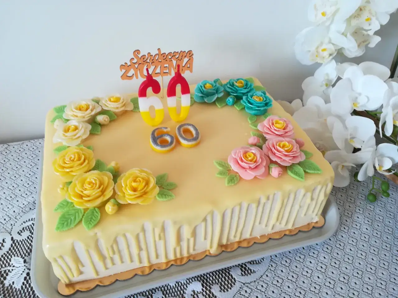 Elegancki tort na 60 urodziny, ozdobiony ż&oacute;łtymi, r&oacute;żowymi i turkusowymi r&oacute;żami z masy cukrowej. Jak udekorować tort na 60 urodziny? Ten przykład inspiruje!