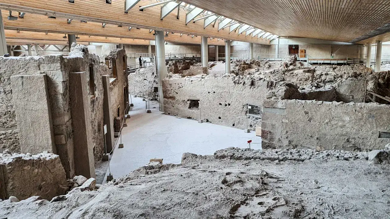 Ruiny Akrotiri, starożytnego miasta na Santorini, odsłaniają kamienne mury i ślady dawnego życia pod nowoczesnym dachem.