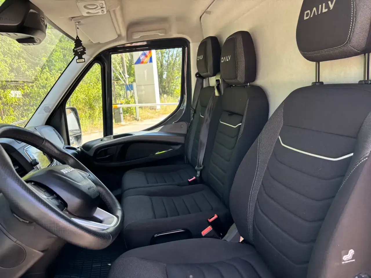 Wnętrze busa Iveco Daily, z trzema czarnymi siedzeniami i kierownicą. Idealny do transportu ładowność 1,5 tony.
