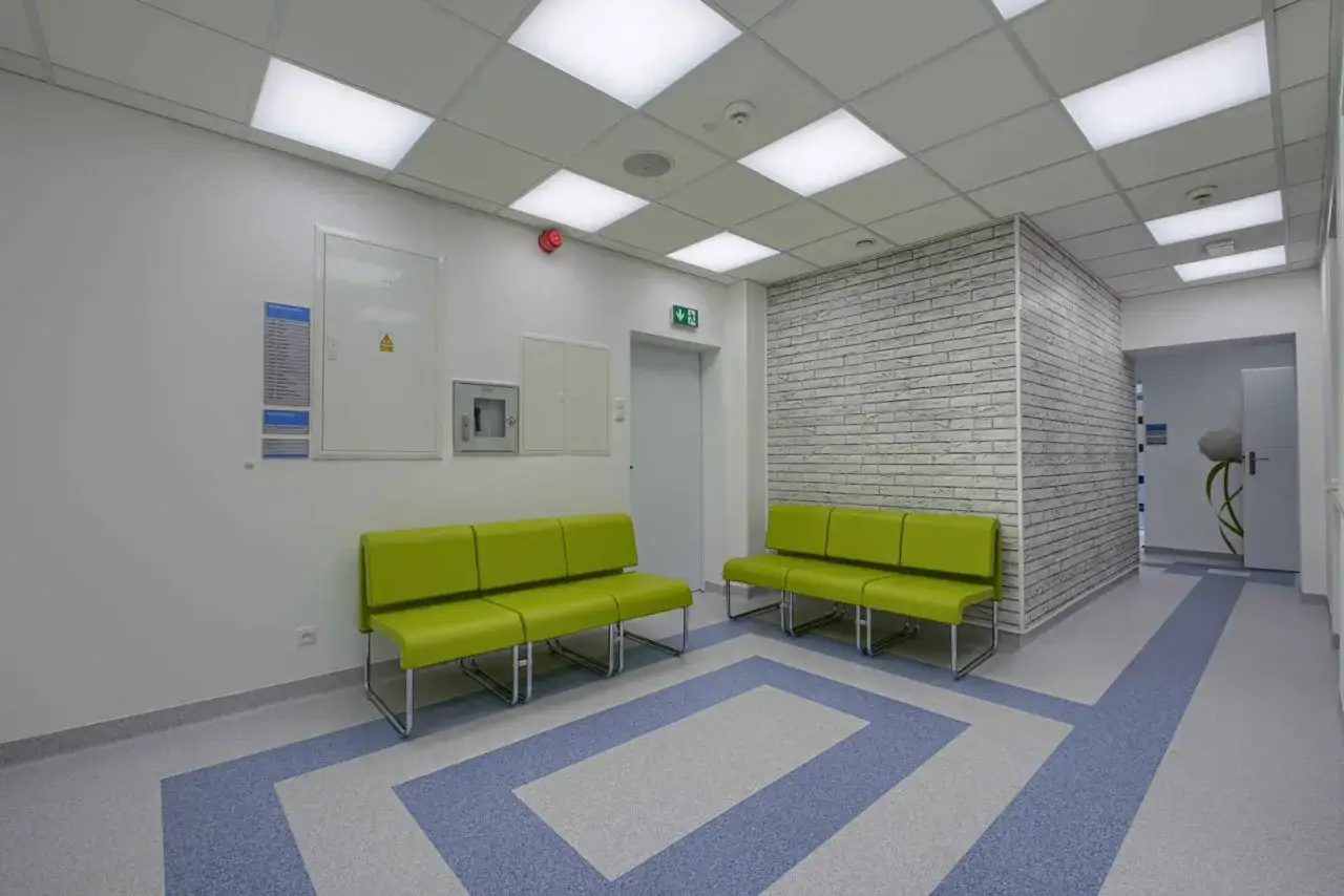 Jasne, nowoczesne wnętrze z zielonymi kanapami i ceglaną ścianą. Idealne miejsce na odpoczynek w sanatoriach nad morzem.