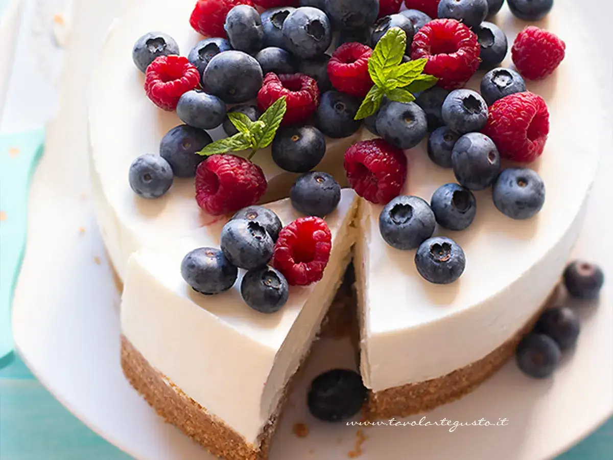 Cheesecake yogurt greco con frutti di bosco freschi, una fetta è stata tagliata.