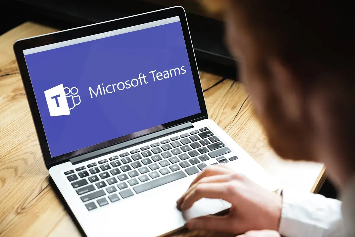 Mężczyzna korzysta z laptopa z logo Microsoft Teams. Idealne narzędzie do studiów magisterskich online bez zjazdów.