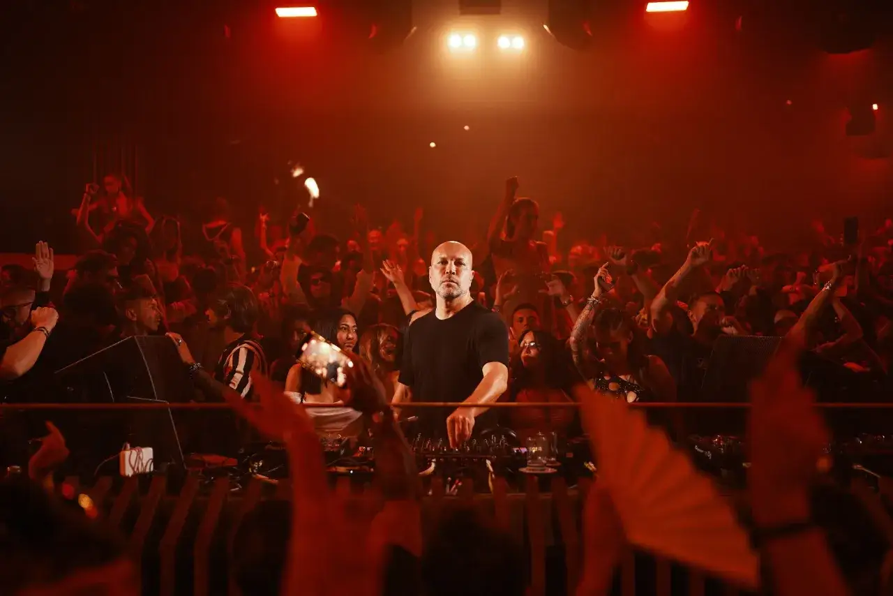 DJ al Pacha, la folla balla al ritmo della musica, luci rosse e un'atmosfera elettrica.