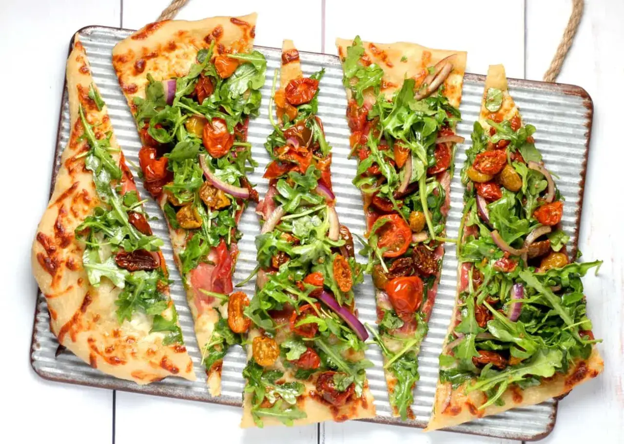 Pyszna pizza wegetariańska z rukolą, pomidorkami koktajlowymi i czerwoną cebulą. Jakie dodatki wybrać? Ta wygląda obłędnie!