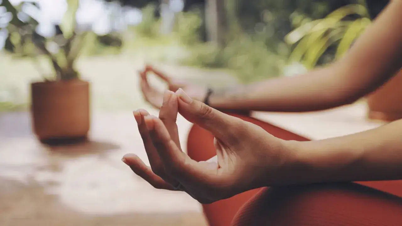 Manos en posición de mudra energía, meditando al aire libre.