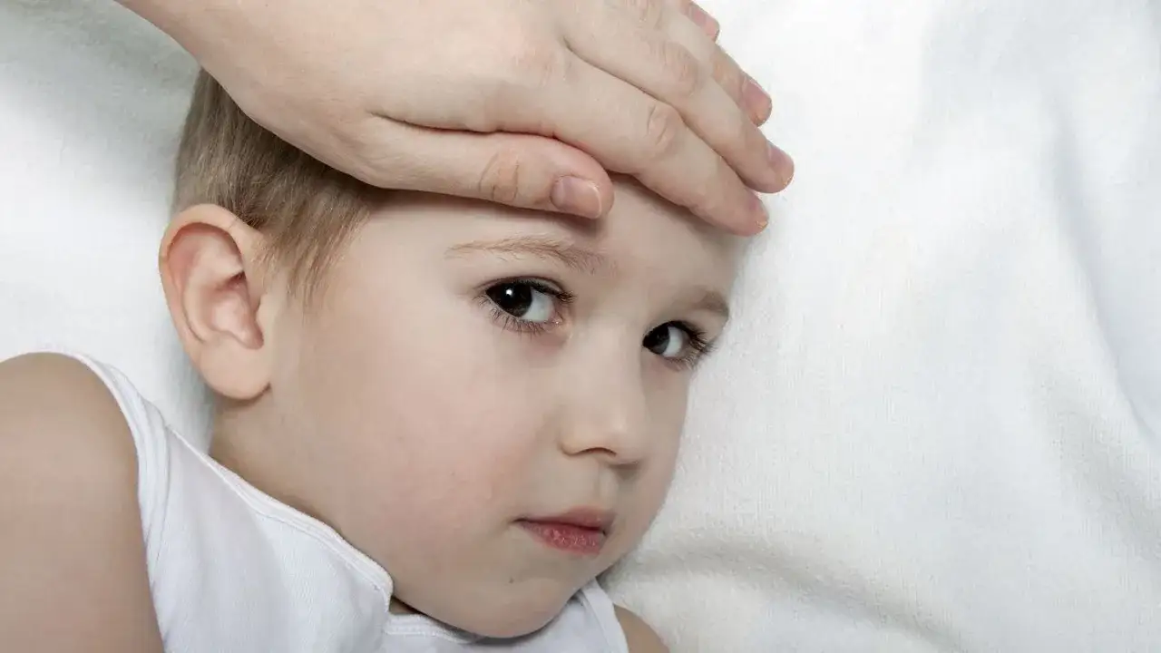 Dłoń mamy na czole dziecka, które ma gorączkę. Czy to już trzydniówka?