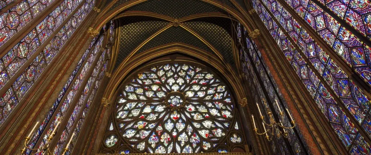 Interior de la Sainte Chapelle, con vidrieras de colores vibrantes y una gran roset&oacute;n que ilumina el espacio.