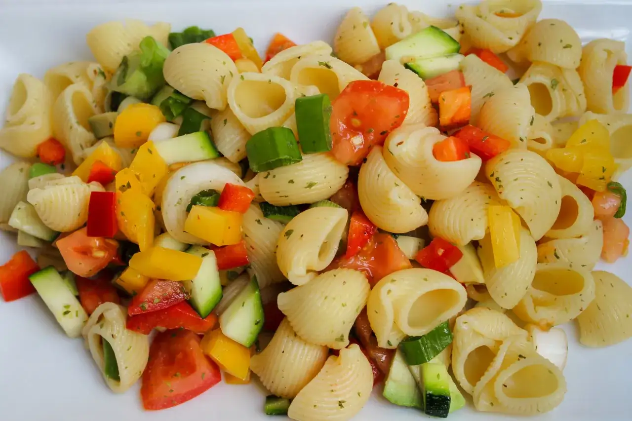 Ein bunter Nudelsalat mit Muschelnudeln, Tomaten, Gurken, Paprika und Frühlingszwiebeln.