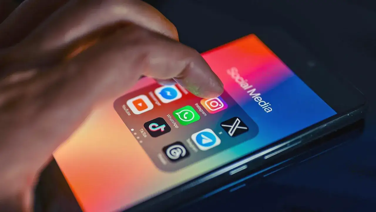 Finger tippt auf Instagram-Icon. Was bedeutet Influencer auf Deutsch? Social Media Apps wie TikTok, WhatsApp, Telegram sind sichtbar.
