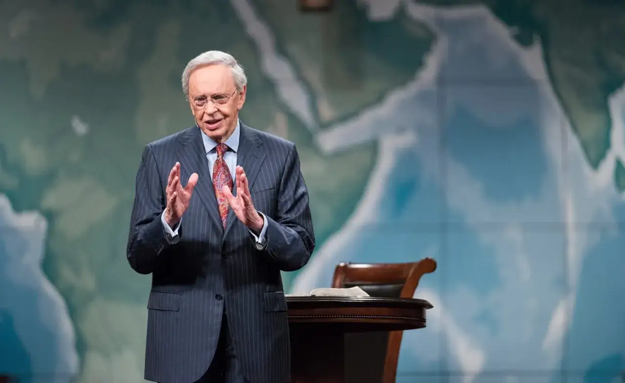Dr. Charles Stanley spricht mit erhobenen H&auml;nden vor einer Weltkarte.