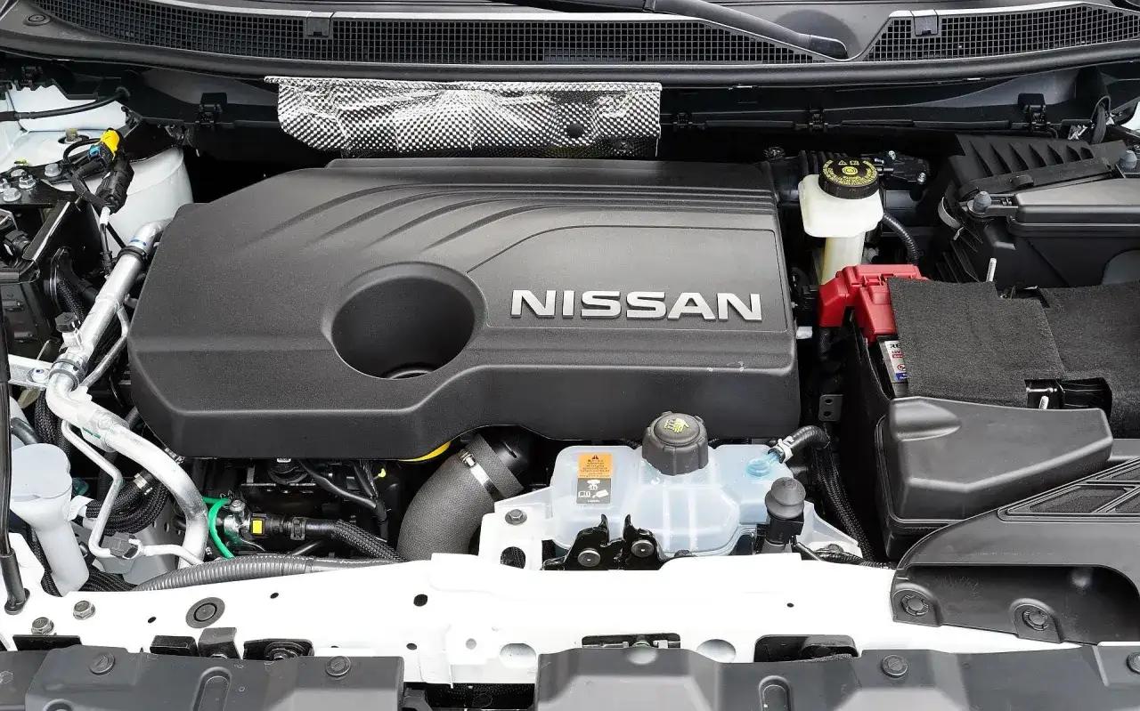 Silnik Nissana Qashqai 2. Widoczna osłona silnika z logo NISSAN, akumulator i zbiornik płynu chłodniczego.