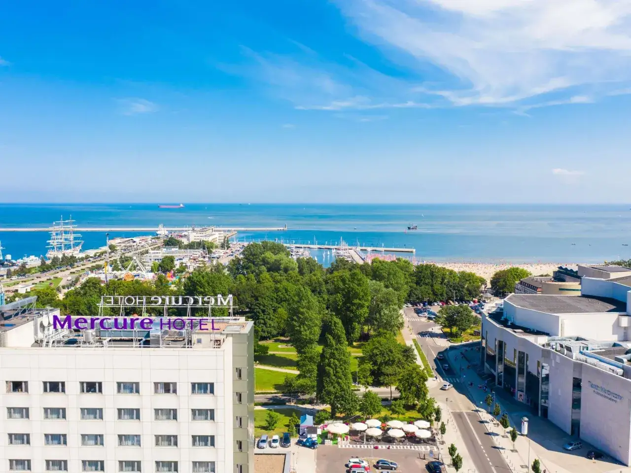 Widok na hotel Mercure Gdynia z dachu, w tle port, morze i plaża.