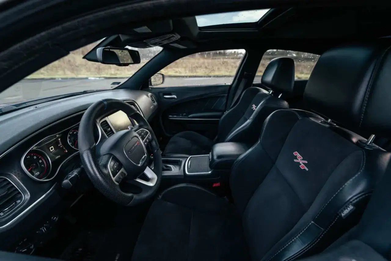 Wnętrze Dodge Charger Hellcat: czarne fotele z logo R/T, kierownica, deska rozdzielcza i szyberdach.