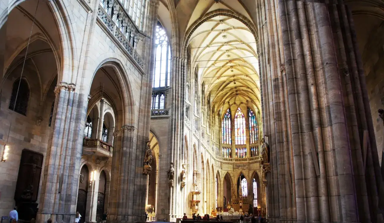 Interior of a grand cathedral with soaring vaulted ceilings and stained-glass windows. The clerestory, high above, lets in divine light.