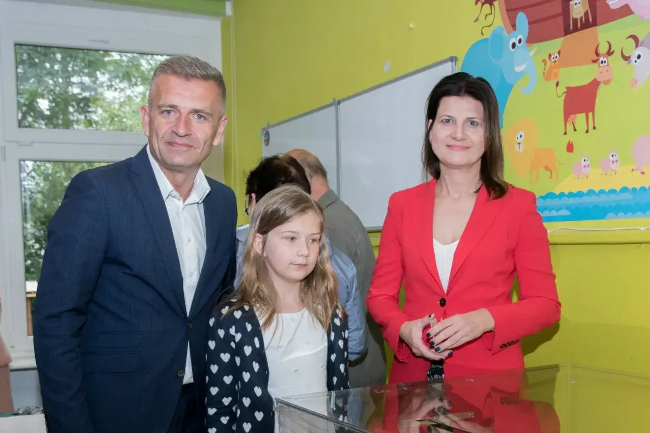 Bartosz Arłukowicz z córką i koleżanką na tle kolorowych zwierzątek.