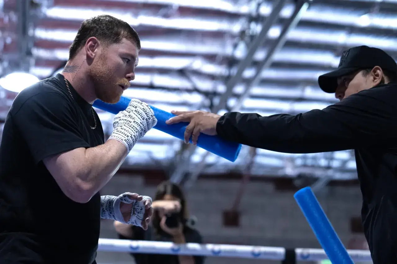 Canelo Alvarez trains with a coach, showing how good he is. His focus is intense as he prepares for his next fight.