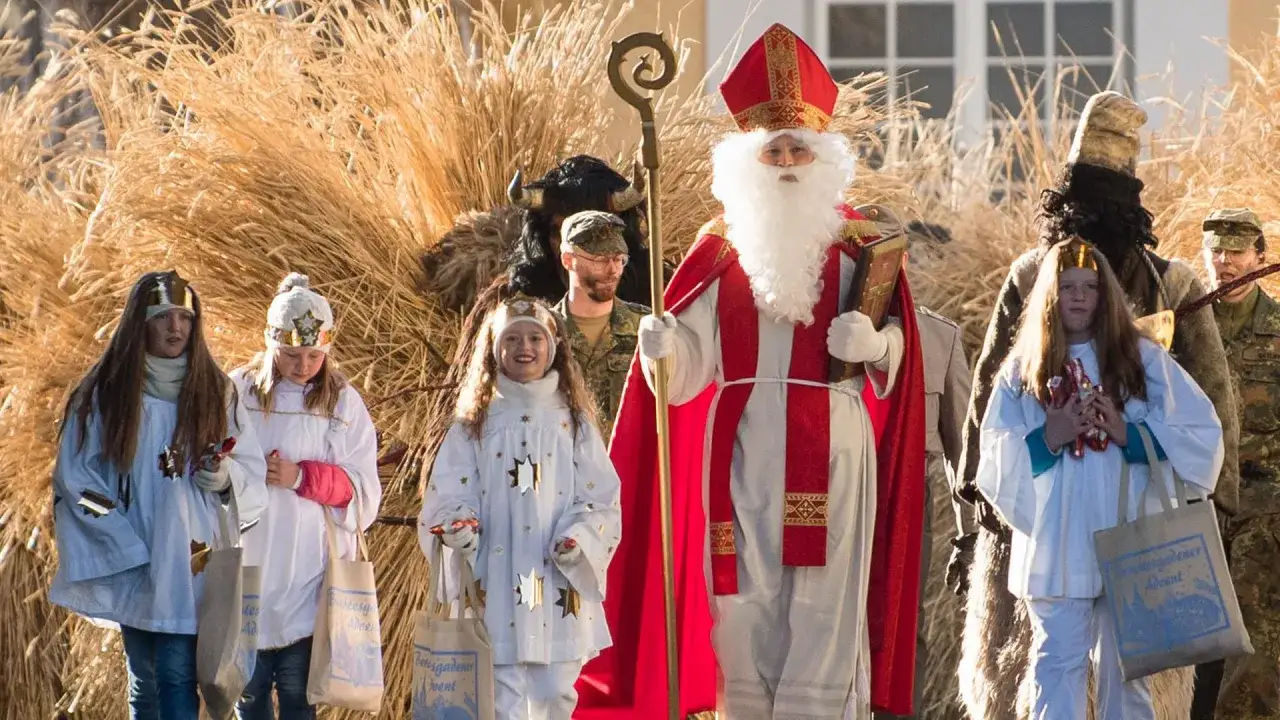 Nikolaus mit Gefolge, darunter Kinder mit Sternen, erinnert daran, wann ist Nikolaustag.