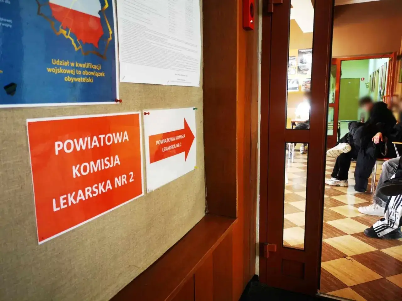 Tablica ogłoszeń z informacją o kwalifikacji wojskowej. Obowiązkowa służba wojskowa to ważny etap. Ludzie czekają w kolejce.