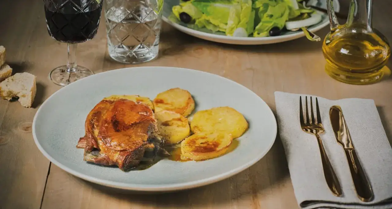 Deliciosa chuleta de ternasco asada, acompa&ntilde;ada de patatas doradas. Un fest&iacute;n para los sentidos.
