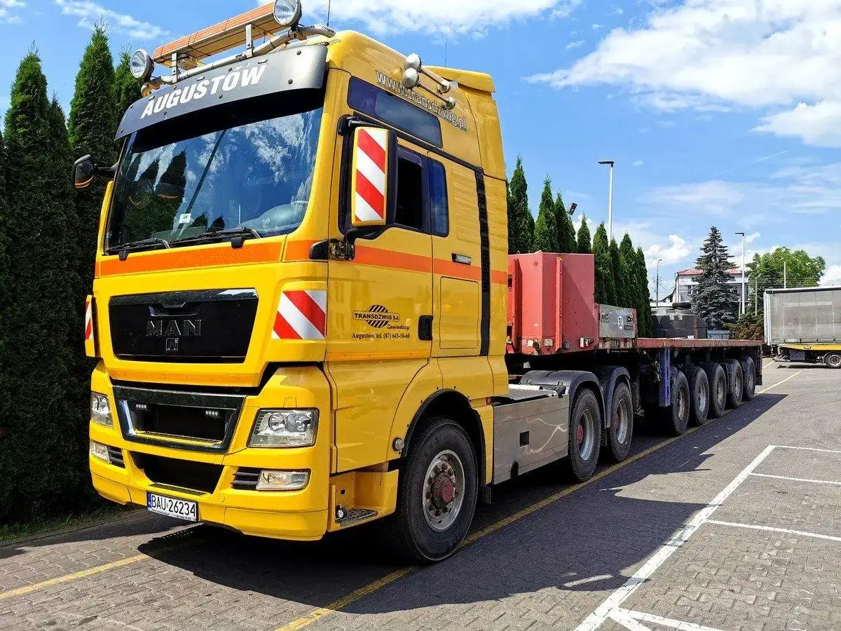 Żółty ciągnik siodłowy MAN z naczepą, gotowy do pracy. Taki zestaw na pusto waży ok. 18-20 ton.