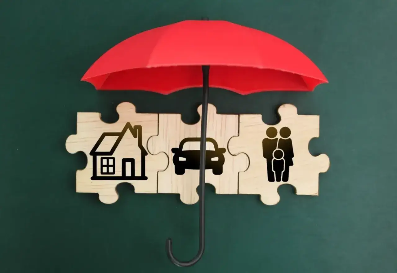 Czerwony parasol chroni puzzle z domem, samochodem i rodziną. Ubezpieczenie OC po terminie może narazić te elementy na ryzyko.