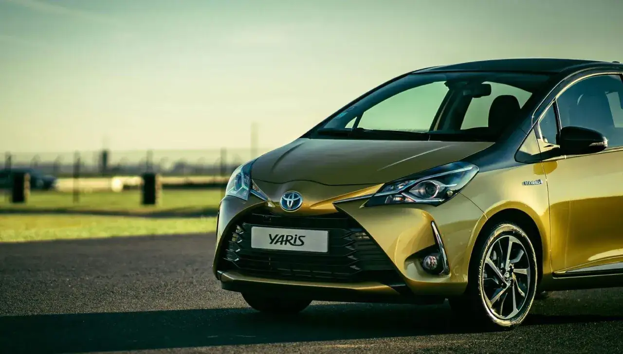 Toyota Yaris h&iacute;brido dorado, uno de los coches mas fiables de segunda mano, en carretera con fondo difuminado.